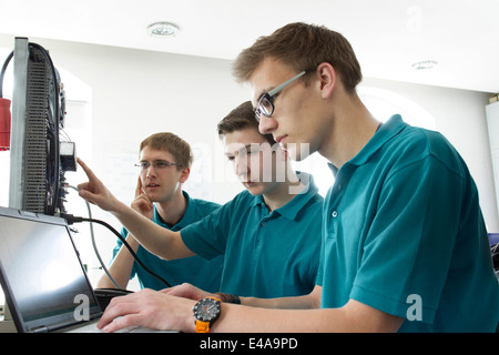 Trois apprentis à l'atelier de test électronique Banque D'Images