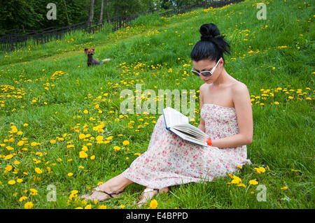 Jeune femme lisant un livre dans le parc Banque D'Images