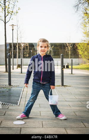 Fille blonde debout avec la craie sur trottoir, Munich, Bavière, Allemagne Banque D'Images