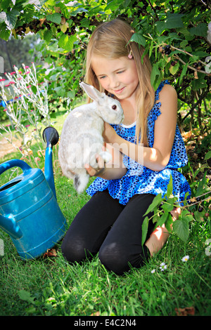 Teenage girl jouer avec un lapin dans le jardin Banque D'Images