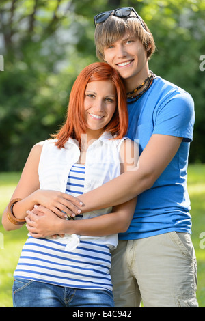 Teenage romantique couple hugging in sunny park smiling at camera Banque D'Images