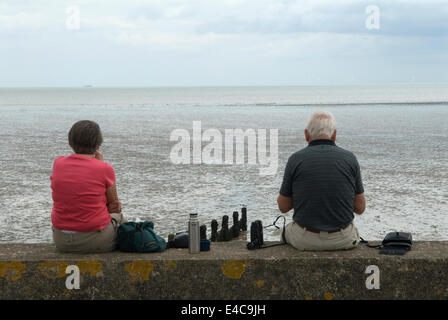 Couple retraité, familier les uns avec les autres et assis à part, thermos bouteille profiter de la journée à l'île de bord de mer de Shepey Kent 2014 2010s Royaume-Uni.HOMER SYKES Banque D'Images