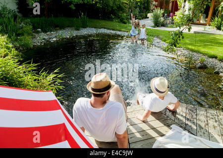 Imbéciles autour de la famille par l'étang, les projections d'eau, Munich, Bavière, Allemagne Banque D'Images