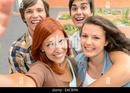 Groupe d'étudiants amis adolescents en tenant l'appareil photo de rire de selfies Banque D'Images