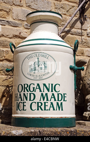 La crème glacée faite main organique peint sur un vieux bidon de lait à l'extérieur de l'entrée de l'ancien moulin, Lower Slaughter, England, UK. Banque D'Images