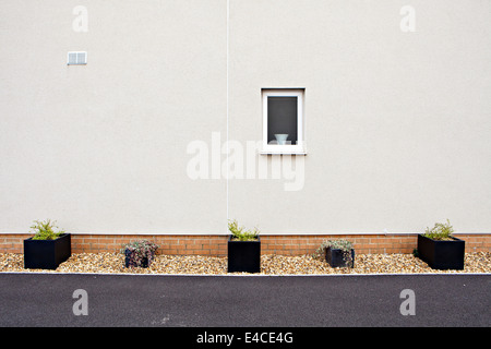 Vue sur la paroi latérale à la maison récemment construite avec des jardinières dans un lit de gravier Banque D'Images