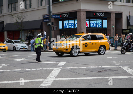 Une femme de police dirige le trafic à une intersection achalandée à New York, NY Banque D'Images