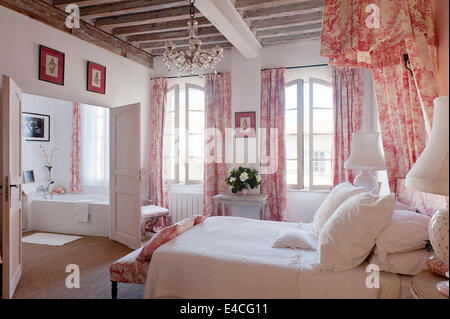 Rose et blanc toile de jouy sur des coussins, rideaux et un lit à baldaquin coronet dans la chambre avec plafond à poutres apparentes et de chevet Banque D'Images