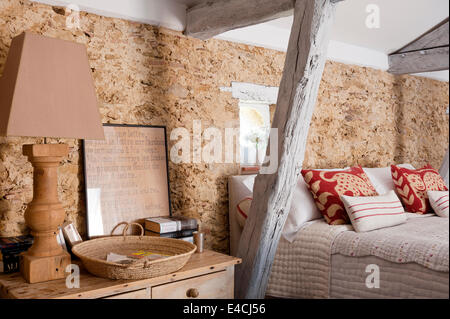 Chandelier en bois sur une table de chevet dans une chambre avec des murs en pierre et poutres en bois Banque D'Images
