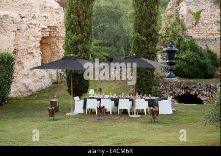 Un set de table pour le dîner sous une paire de parasols noir avec 11e siècle ruines et de cyprès en arrière-plan. La salle chai Banque D'Images