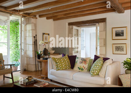 Canapé blanc dans la salle de séjour avec des poutres en bois au plafond et mur de pierre détail. Les coussins sont réalisés par Kate Armitage du vintage f Banque D'Images