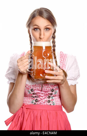 Belle jeune femme avec ses cheveux en tresses portant un dirndl boire de la bière à partir d'un très grand verre tankard avec un regard d'ant Banque D'Images