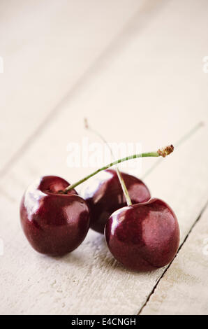 Cerises sur une planche de bois blanc. Banque D'Images