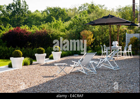 Des chaises longues et des parasols sur la terrasse en gravier Banque D'Images