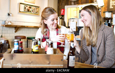 Les jeunes femmes le grillage avec de la bière dans un pub, Dorset, Bournemouth, Angleterre Banque D'Images