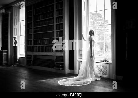 Les préparatifs de mariage, mariée en robe de mariage par fenêtre, Dorset, Angleterre Banque D'Images