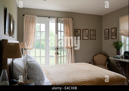 Et blanc à rayures pêche linge de lit dans chambre avec fenêtres à la française Banque D'Images