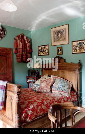 Floral rouge couette sur meubles anciens en lit dans la chambre avec des papillons et des pans de robe ethnique traditionnel Banque D'Images