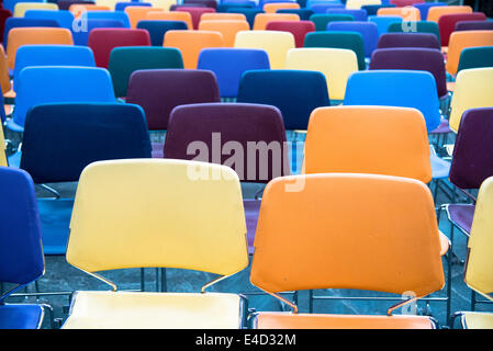 Des rangées de chaises en plastique vide et colorés dans une école Banque D'Images