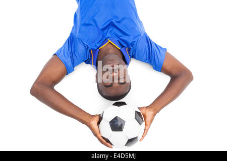 Joueur de football sur le sol holding ball avec les yeux fermé Banque D'Images