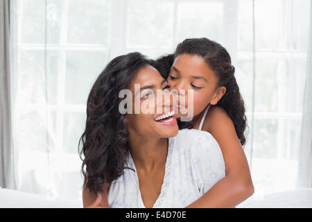 Smiling mother and daughter posing together on bed Banque D'Images