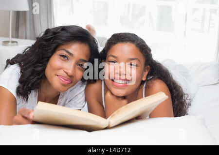 Mother and Daughter reading book together on bed Banque D'Images