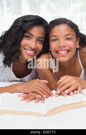 Mother and Daughter reading book together on bed Banque D'Images