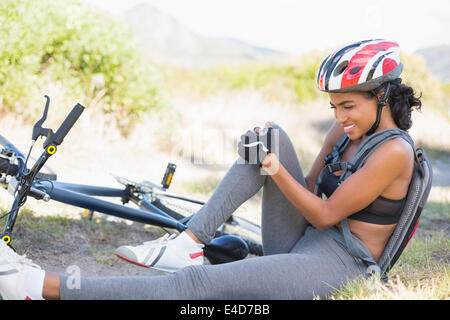 Fit woman holding son genou blessé après l'accident de vélo Banque D'Images