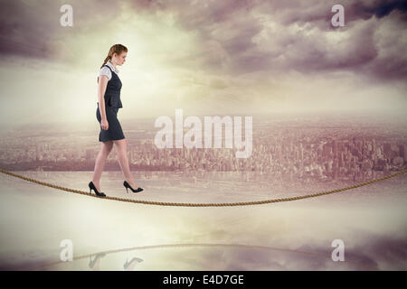 Image composite de redhead businesswoman stepping sur tightrope Banque D'Images