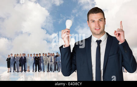 Composite image of businessman holding Light bulb et vers Banque D'Images