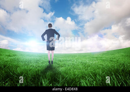 Composite image of young businesswoman standing with hands on hips Banque D'Images
