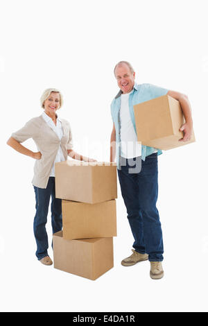 Older couple smiling at camera with moving boxes Banque D'Images