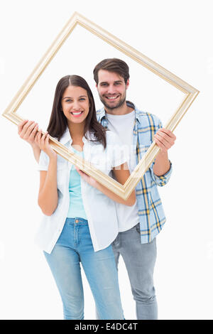 Happy young couple holding photo frame Banque D'Images