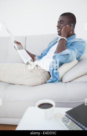 Casual man on the phone holding newspaper Banque D'Images