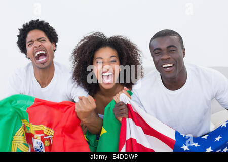 Les fans de football sitting on couch with flags Banque D'Images