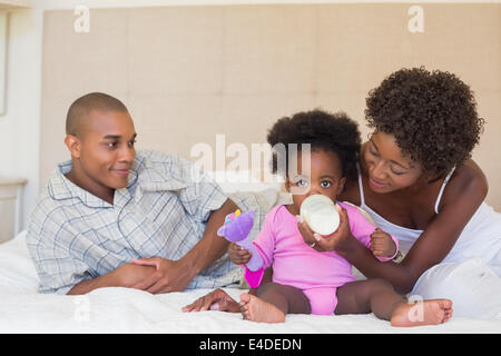 Heureux parents avec bébé fille sur leur lit Banque D'Images