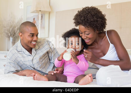 Heureux parents avec bébé fille sur leur lit Banque D'Images