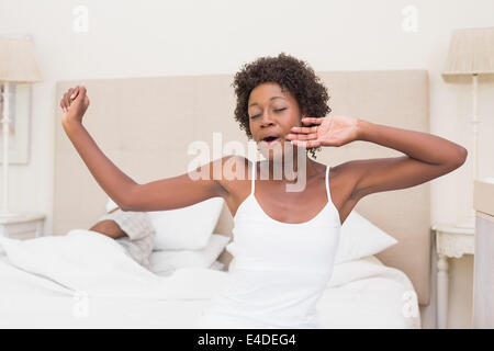 Jolie femme qui s'étend à l'extrémité du lit Banque D'Images