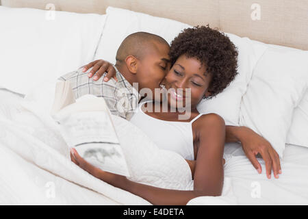 Heureux couple Lying in Bed de câlins Banque D'Images