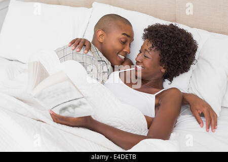 Heureux couple Lying in Bed de câlins Banque D'Images