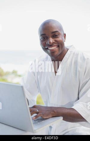 Bel homme en peignoir à l'aide de l'extérieur de l'ordinateur portable Banque D'Images