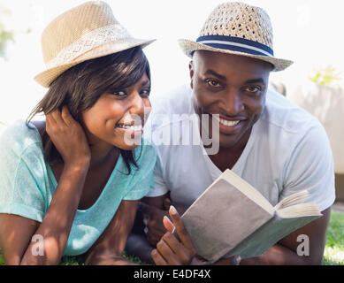 Heureux couple lying in garden ensemble reading book Banque D'Images