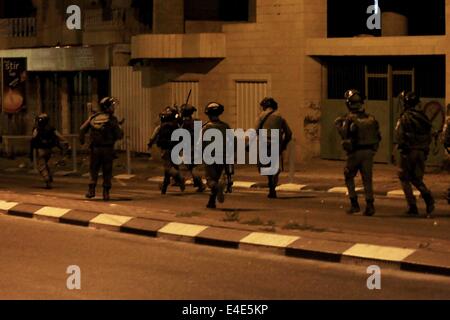 Bethléem, CISJORDANIE PALESTINE- 2014/07/08- charge des soldats israéliens dans les rues de Bethléem pour soumettre les jeunes Palestiniens de défi qui se réunissent tous les nuit pour manifestations. Pour la septième nuit consécutive d'intenses affrontements ont éclaté à Bethléem près du Tombeau de Rachel, également connu sous le nom de Checkpoint 300. La tour de garde militaire est souvent la cible de cocktails Molotov et de pierres projetés par les jeunes. Un canon à eau se dresse au sommet du mur de la tour de garde et souvent pulvérise de l'eau 'skunk' sur les manifestants. Le point de contrôle militaire et Watch Tower est une partie de l'immense barrière de béton qui a été construit par Israël Banque D'Images