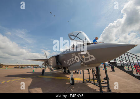 RAF Fairford, Gloucestershire UK. 9 juillet 2014. Nouvelles et anciennes technologies. Lockheed Martin F35 Lightning cinquième génération d'avions furtifs maquette pleine grandeur sur l'affichage à la presse avant l'ouverture de RIAT le vendredi 11 juillet avec trois de l'ère soviétique en Sukhoi Su 22M en forme de jets de l'Armée de l'Air polonaise faire un passage avant l'atterrissage, la première fois, ces avions ont pris part à un spectacle aérien britannique. Credit : Malcolm Park editorial/Alamy Live News Banque D'Images