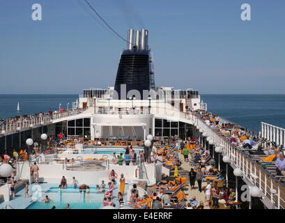 Le pont supérieur d'un navire de croisière animée avec des gens assis autour de la piscine, un jour ensoleillé Banque D'Images