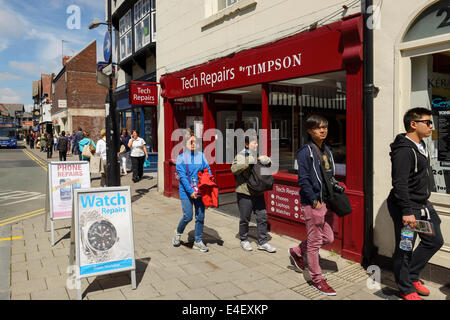 Des gens devant un magasin de réparations Tech Timpson Banque D'Images