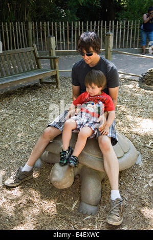 Jeune père et fils assis sur des pierres à la Tortue Zoo de Louisville au Kentucky Banque D'Images