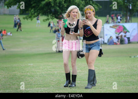 Les JEUNES FILLES APPRÉCIANT LES MÉDIAS SOCIAUX À UN NOUVEAU FESTIVAL DE MUSIQUE EN PLEIN AIR FESTIVALS D'UN TÉLÉPHONE MOBILE ÉVÉNEMENTS SOCIAUX ADOLESCENTS UK Banque D'Images