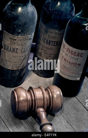 Vente aux enchères de vin les bouteilles de vin de Bordeaux vintage old dusty, Margaux et Saint Emilion sur le vin tonneau avec les commissaires-priseurs gavel en premier plan Banque D'Images