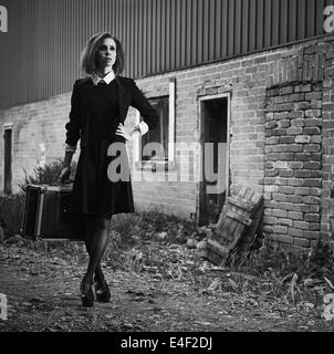 Jeune femme à la mode avec sa valise, vieille scène rurale, image en noir et blanc Banque D'Images